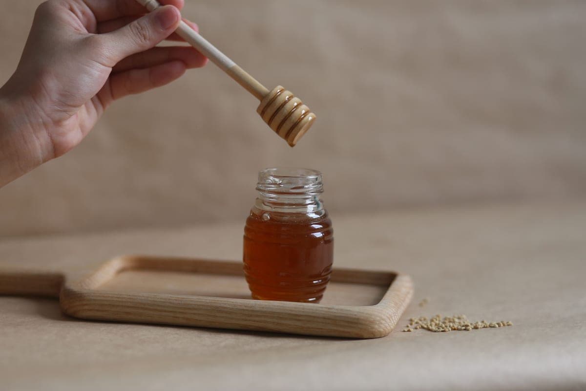 Jar of raw honey with a dipper
